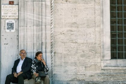 Senior couple sitting by the New Mosque in Eminönü, Istanbul, reflecting a moment of leisure.