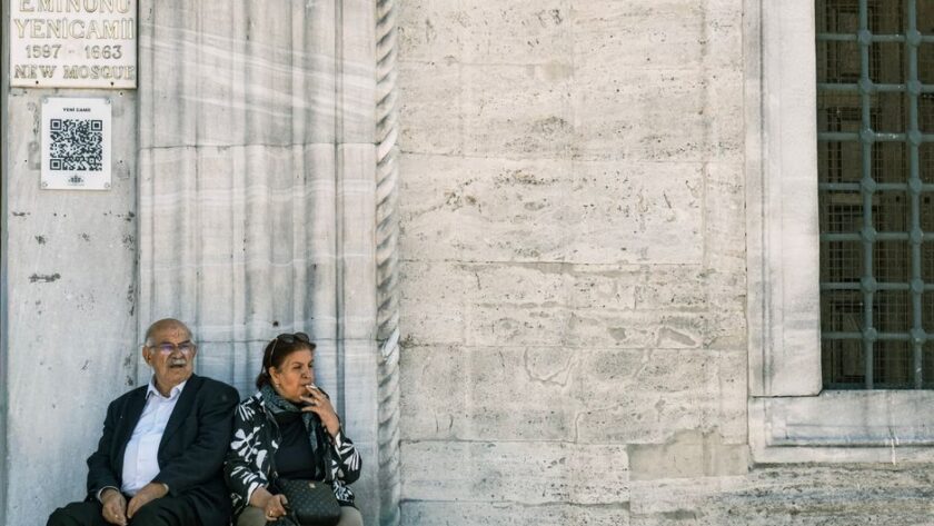 Senior couple sitting by the New Mosque in Eminönü, Istanbul, reflecting a moment of leisure.