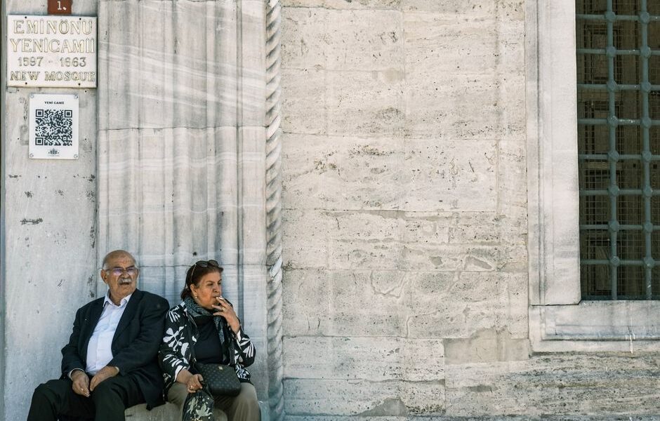 Senior couple sitting by the New Mosque in Eminönü, Istanbul, reflecting a moment of leisure.