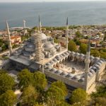 Aerial view of a large, ornate mosque with minarets.