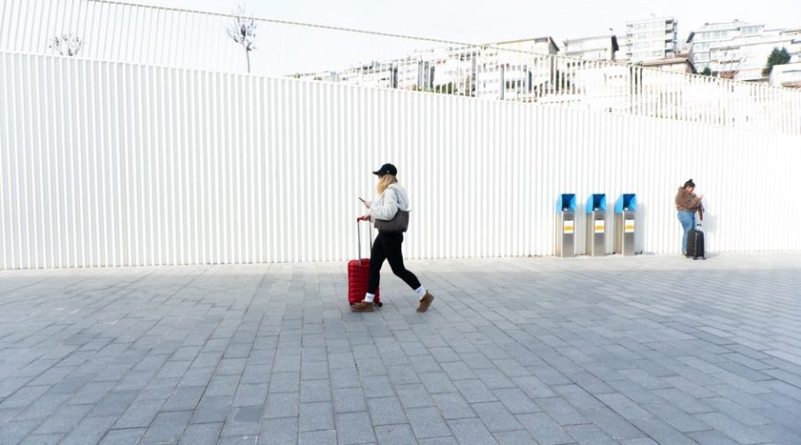 Person with suitcase walking in Kabataş, Istanbul, Türkiye, showcasing urban lifestyle and modern architecture.