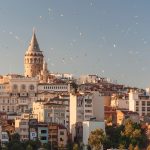 The Galata Tower rising above the cityscape of Istanbul with birds flying overhead