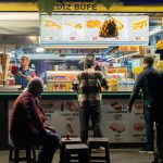 a group of people standing in front of a food stand