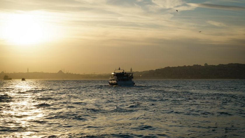 A boat sails on the water during a golden sunset