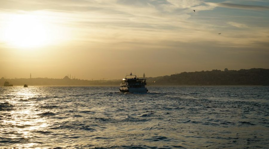 A boat sails on the water during a golden sunset