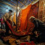 A group of people standing around a pile of rugs