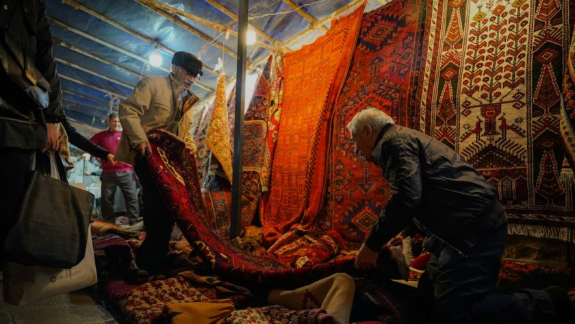 A group of people standing around a pile of rugs